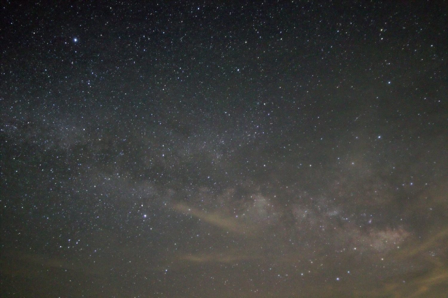 Wide-angle photograph of the Milky Way partially obscured by cloud cover over the Pinto Basin in Joshua Tree National Park