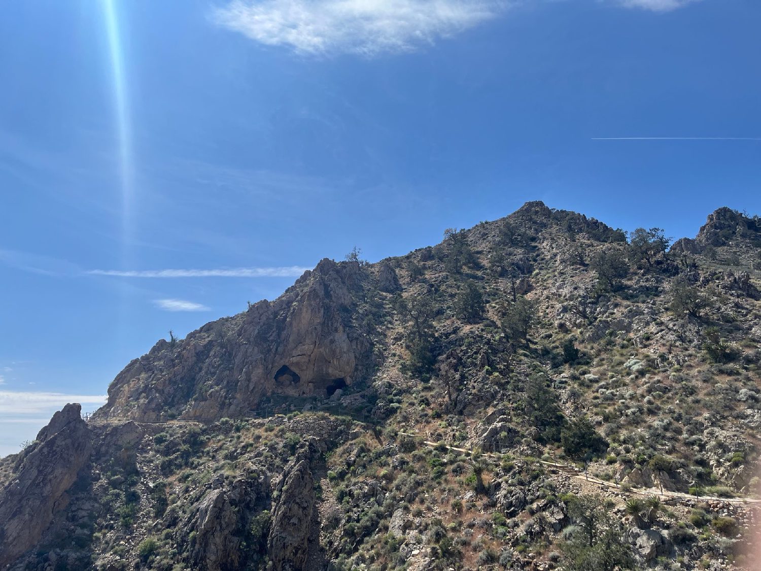Hikers climbing a rocky trail up the Providence Mountains toward the Mitchell Caverns entrance