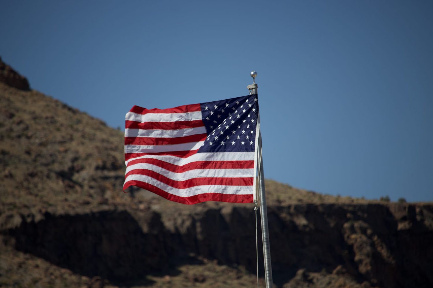 An American flag on a pole at the Hole-in-the-Wall Visitor Center in Mojave National Preserve, desert hills in the background